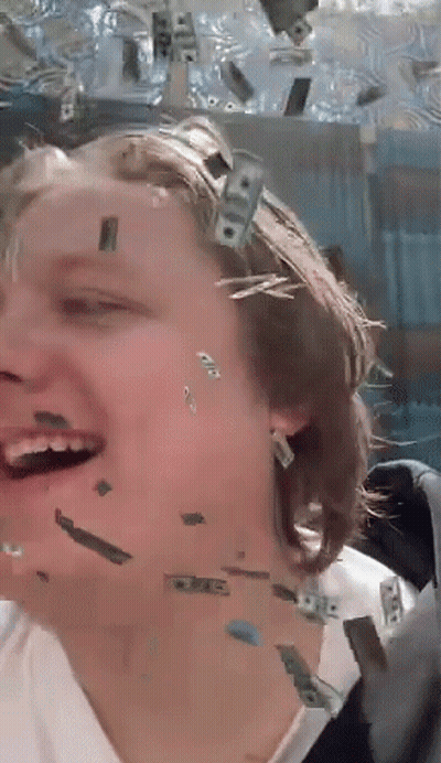 A Woman Is Laughing While Money Falls On Her Face GIF