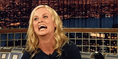 A Woman Is Laughing While Sitting In Front Of A Cbs Sign GIF