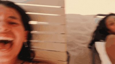 A Woman Is Laughing With Her Mouth Open And Another Woman Is Behind Her GIF