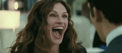 A Woman Is Laughing With Her Mouth Open And Sticking Out Her Tongue . GIF