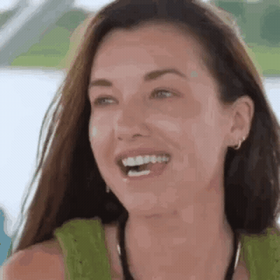 A Woman Is Laughing With Her Mouth Open And Wearing A Green Tank Top . GIF