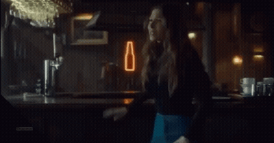 A Woman Is Laughing With Her Mouth Open In A Bar GIF