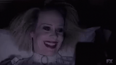 A Woman Is Laying In A Bed With A Collar Around Her Neck And Looking At A Cell Phone . GIF