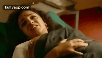 A Woman Is Laying In A Hospital Bed With A Baby In Her Arms . GIF