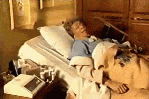A Woman Is Laying In A Hospital Bed With A Blanket On . GIF
