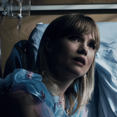 A Woman Is Laying In A Hospital Bed With A Drip In Her Arm GIF