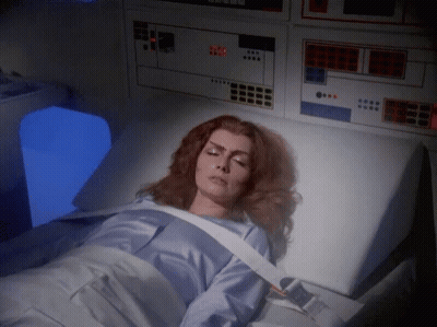 A Woman Is Laying In A Hospital Bed With A Monitor Behind Her That Says ' Emergency Room ' GIF