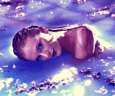 A Woman Is Laying In A Pool Of Water GIF