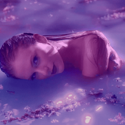 A Woman Is Laying In A Purple Bathtub GIF