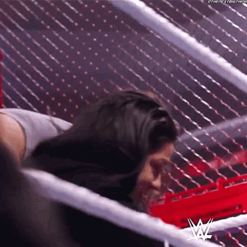 A Woman Is Laying In A Wrestling Ring With Her Head In A Ring . GIF