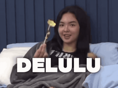 A Woman Is Laying In Bed Holding A Flower And The Word Delulu Is On The Bottom Right GIF