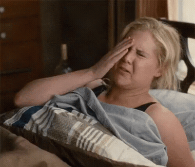 A Woman Is Laying In Bed Rubbing Her Eyes . GIF