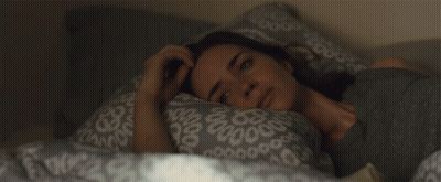A Woman Is Laying In Bed With A Pillow That Has A Pattern Of Circles On It GIF