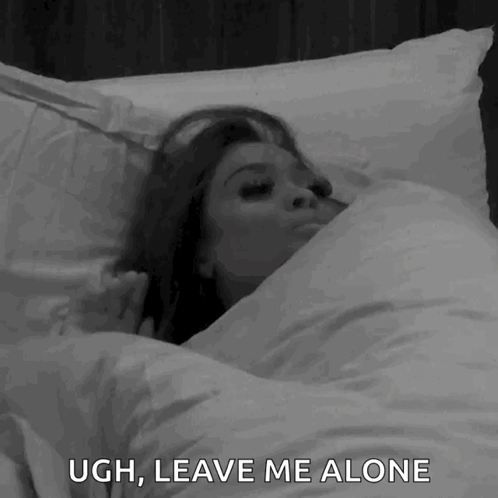 A Woman Is Laying In Bed With The Words Ugh Leave Me Alone Written On The Bottom Of Her Face . GIF