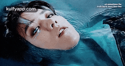A Woman Is Laying In The Water With Her Eyes Closed And Tears Coming Out Of Her Eyes . GIF