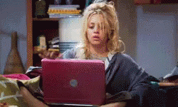 A Woman Is Laying On A Bed Looking At A Laptop GIF