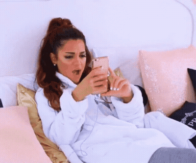 A Woman Is Laying On A Bed Wearing A White Robe And A Hoodie . GIF