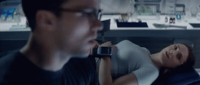 A Woman Is Laying On A Bed While A Man Looks At Her Watch GIF