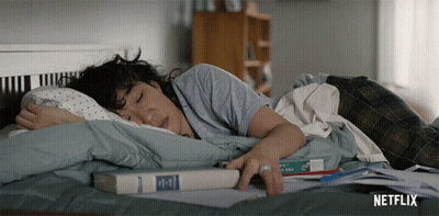 A Woman Is Laying On A Bed With A Book On Top Of Her GIF