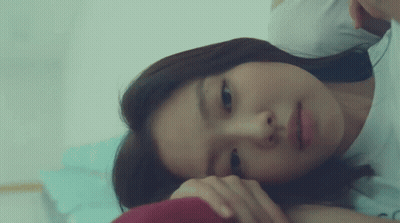 A Woman Is Laying On A Bed With Her Head On Her Hand GIF