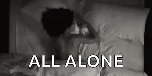 A Woman Is Laying On A Bed With The Words All Alone Above Her . GIF
