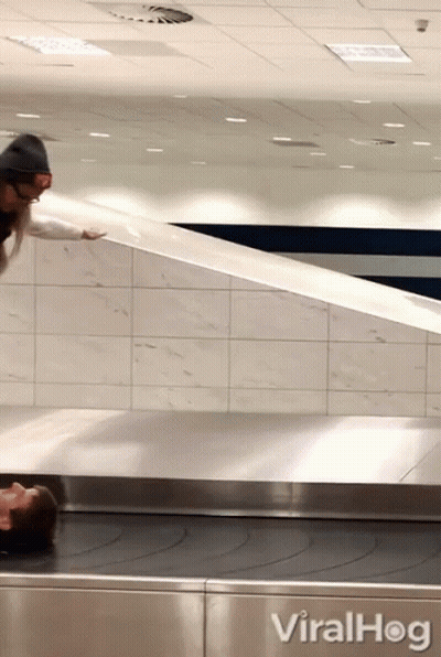 A Woman Is Laying On A Conveyor Belt Next To A Sign That Reads Viralhog GIF