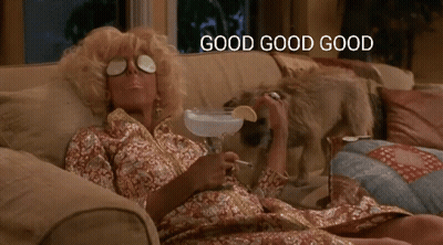 A Woman Is Laying On A Couch Holding A Martini And Smoking A Cigarette With The Words Good Good Good Above Her GIF