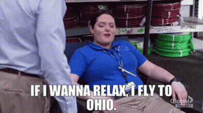 A Woman Is Laying On A Couch In A Store And A Man Is Standing Behind Her . GIF