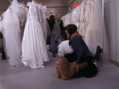 A Woman Is Laying On A Man 'S Lap In A Bridal Shop . GIF
