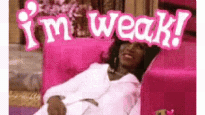 A Woman Is Laying On A Pink Couch With A Sign That Says `` I 'M Weak '' On Her Head . GIF