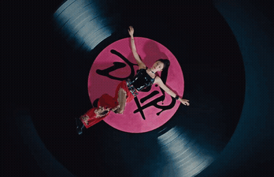 A Woman Is Laying On A Record That Has The Word Drip On It GIF