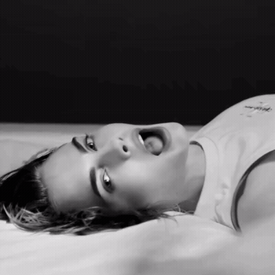 A Woman Is Laying On Her Back With Her Mouth Open GIF