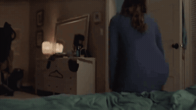 A Woman Is Laying On Her Stomach On A Bed With Her Legs Up . GIF
