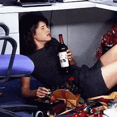 A Woman Is Laying On The Floor Holding A Bottle Of Red Wine GIF
