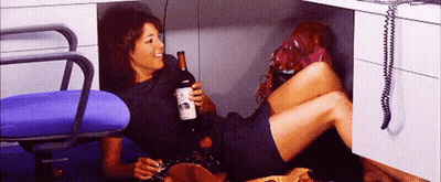 A Woman Is Laying On The Floor Holding A Bottle Of Wine And A Cigarette GIF