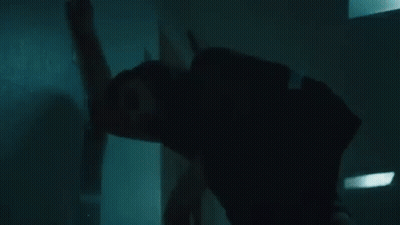 A Woman Is Leaning Against A Wall In A Dark Room In A Hospital . GIF