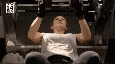 A Woman Is Lifting A Dumbbell In A Gym With A Tv 14 Dlv Logo Behind Her GIF
