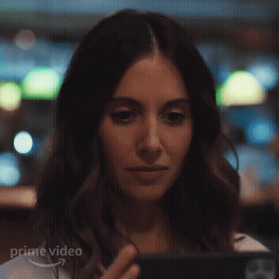 A Woman Is Looking At A Cell Phone In A Restaurant . GIF