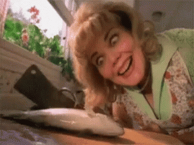 A Woman Is Looking At A Fish On A Cutting Board And Smiling . GIF