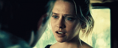 A Woman Is Looking At A Man In A Dark Room And Making A Funny Face . GIF