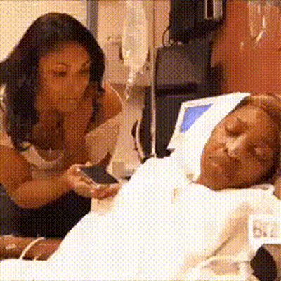 A Woman Is Looking At A Man In A Hospital Bed GIF
