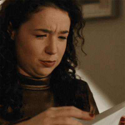 A Woman Is Looking At A Piece Of Paper And Making A Funny Face GIF