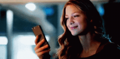 A Woman Is Looking At Her Cell Phone In The Dark . GIF