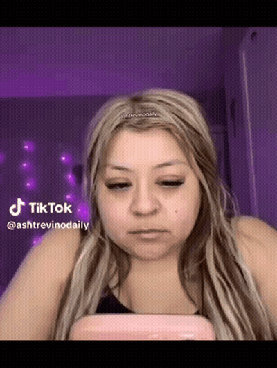 A Woman Is Looking At Her Phone In Front Of A Purple Background . GIF