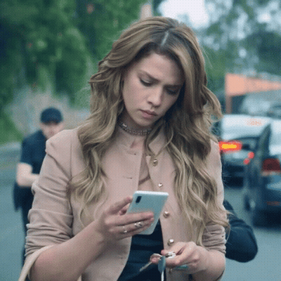 A Woman Is Looking At Her Phone While Holding Keys GIF