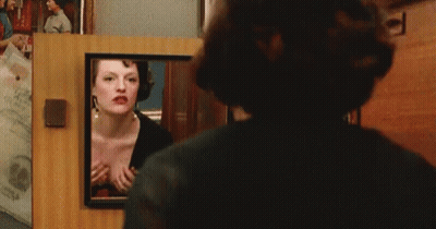 a woman is looking at herself in a mirror