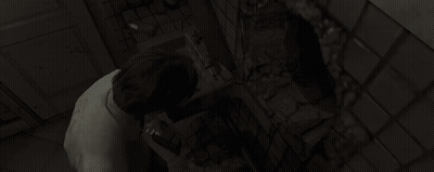 A Woman Is Looking At Herself In A Mirror In A Dark Bathroom . GIF