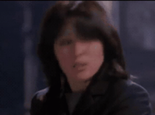 A Woman Is Looking At Herself In A Mirror In A Room GIF