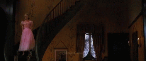 A Woman Is Looking At Herself In A Mirror While Wearing A Green Dress . GIF
