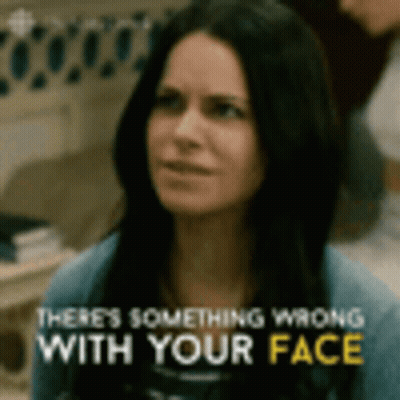 A Woman Is Looking At The Camera With The Words `` There 'S Something Wrong With Your Face '' Written Above Her . GIF